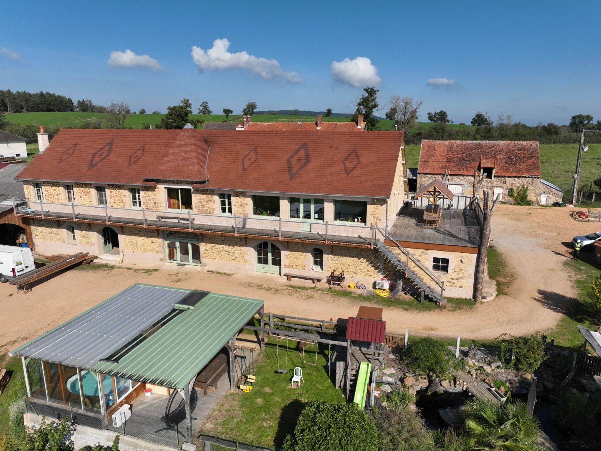 Un bâtiment en pierre de deux étages, doté d’un toit végétalisé et d’un espace piscine.
