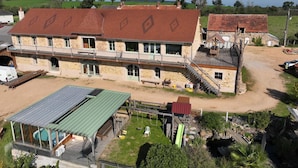 A two-story stone building with a green roof and a swimming pool area. - Rustic cottage, pool - 5 guests (Tronget)