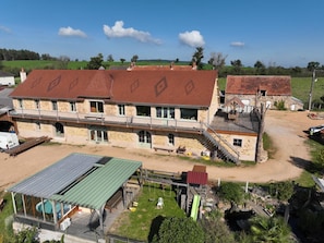 A two-story stone building with a green roof and a swimming pool area. - Rustic cottage, pool - 5 guests (Tronget)