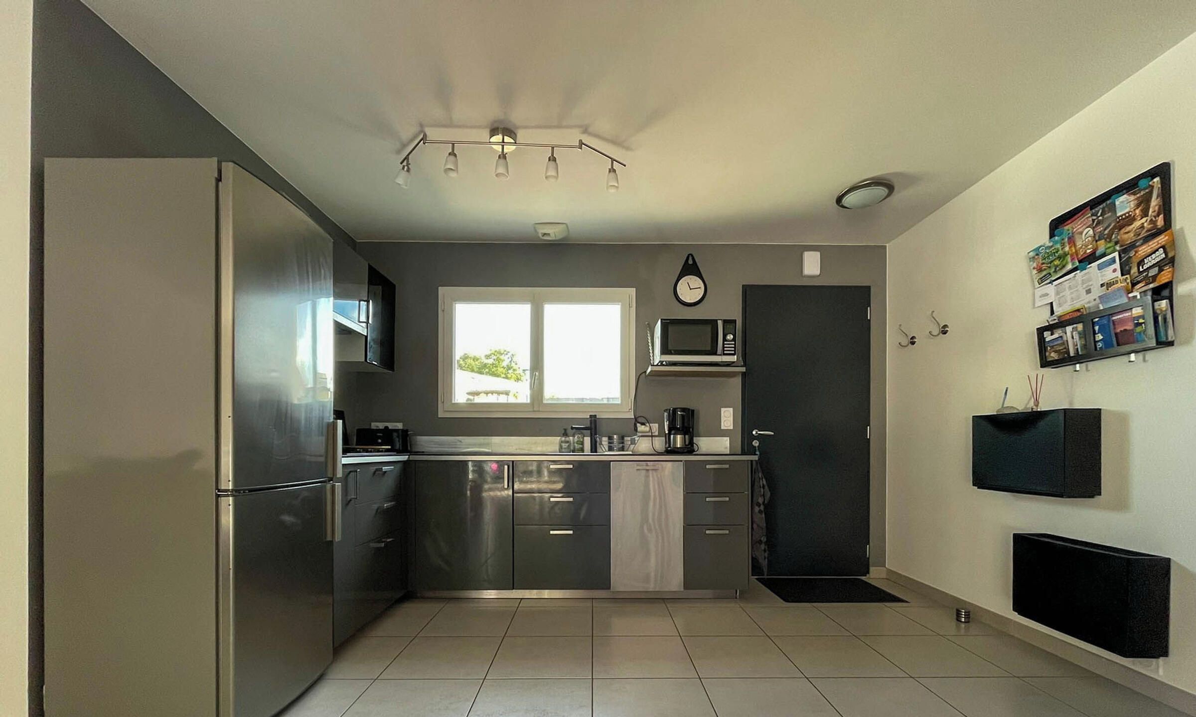 Una cocina moderna con electrodomésticos de acero inoxidable, un microondas y un reloj en la pared.