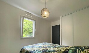 Ett sovrum med en säng, ett fönster, en dörr och en hängande lampa.
