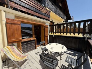 A wooden deck with a table and chairs, a striped beach chair, and a wooden fence. - Renovated mezzanine studio, terrace - 4/6 guests (Les Saisies)