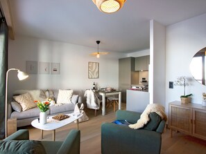 Ein modernes Wohnzimmer mit einer Couch, Sesseln, einem Couchtisch und einem Essbereich.