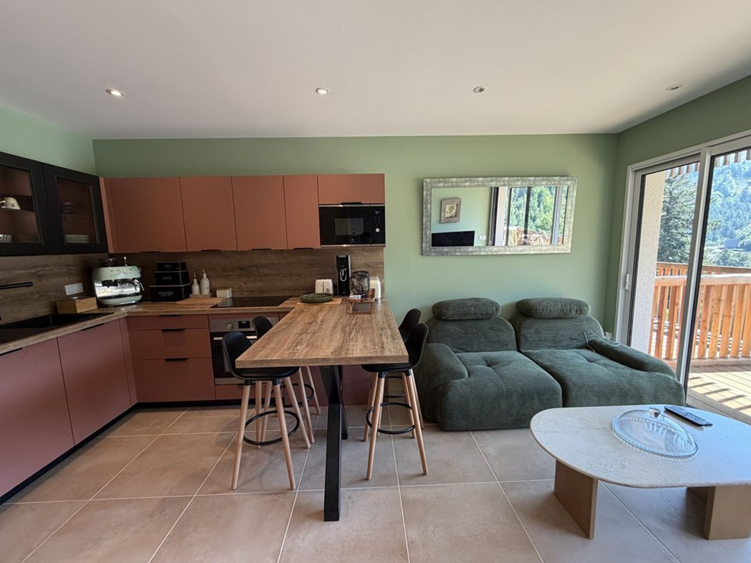 A modern kitchen with a dining area, a sofa set, and a table with a glass cover.