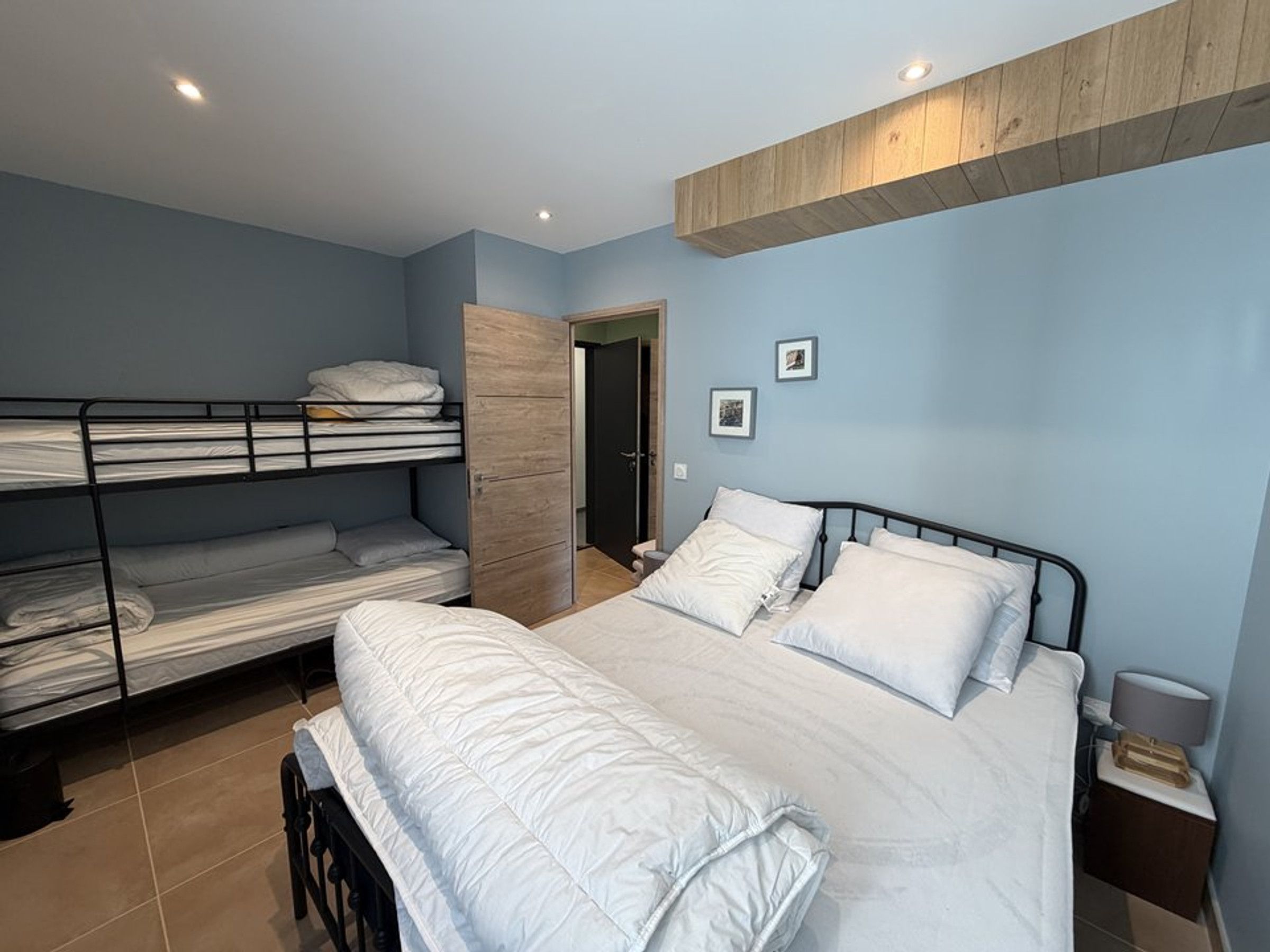 A bedroom with bunk beds, a single bed, a wooden wardrobe, and a nightstand.