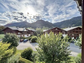 A mountain lodge with multiple wooden buildings, a parking area, and a view of the surrounding hills. - Apartment with mountain view - 6 guests (Praz-sur-Arly)