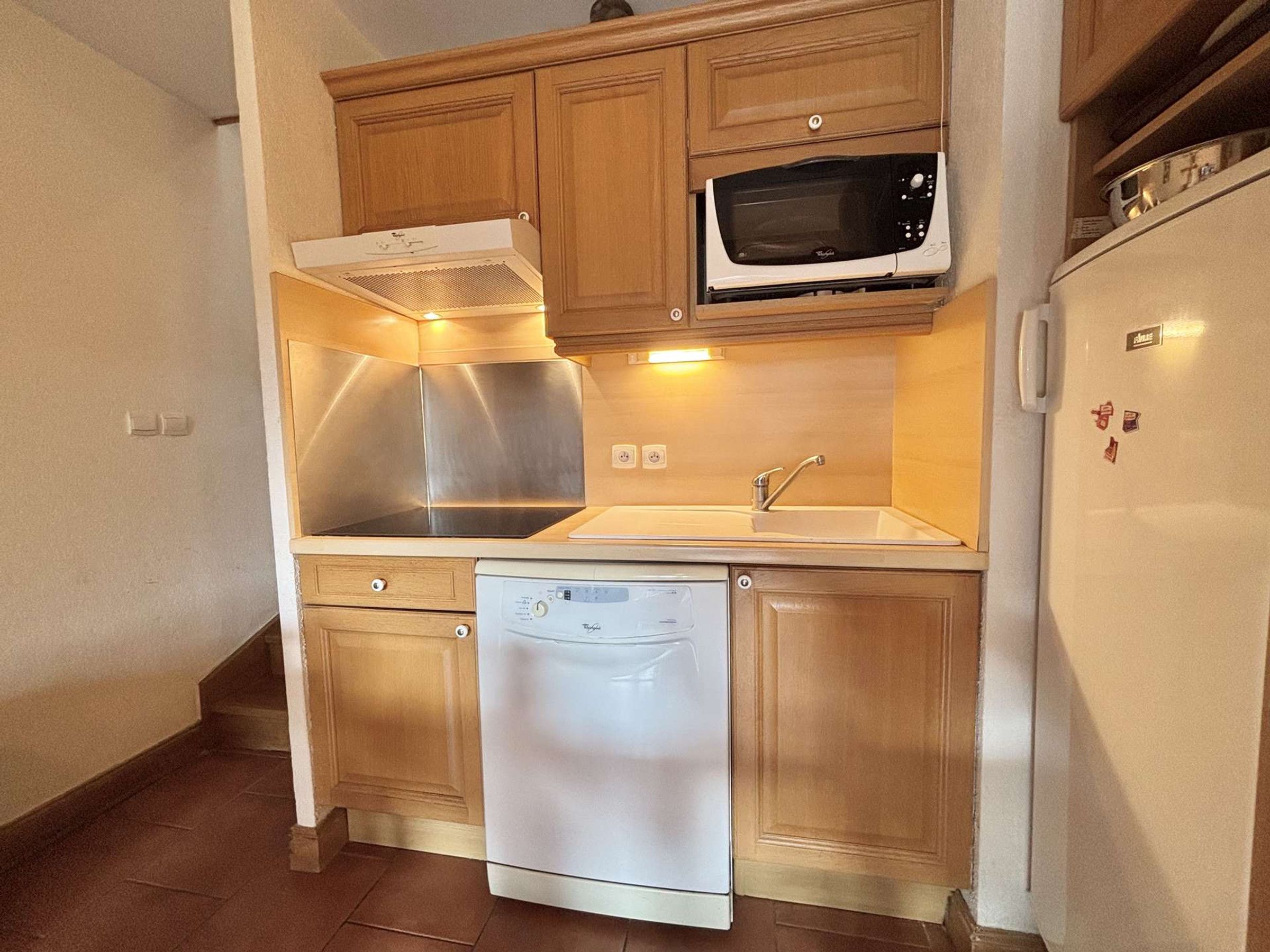 Una cocina compacta equipada con microondas, lavavajillas y una campana extractora de acero inoxidable.