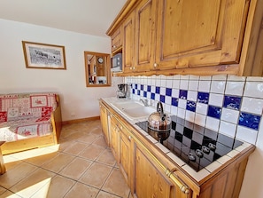 A kitchen with wooden cabinets, a tiled backsplash, a stove, and a sink. - Spacious apartment near slopes - 4 guests (Les Menuires)