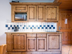 A kitchen with wooden cabinets, a tiled backsplash, and a stainless steel sink. - Spacious apartment near slopes - 4 guests (Les Menuires)