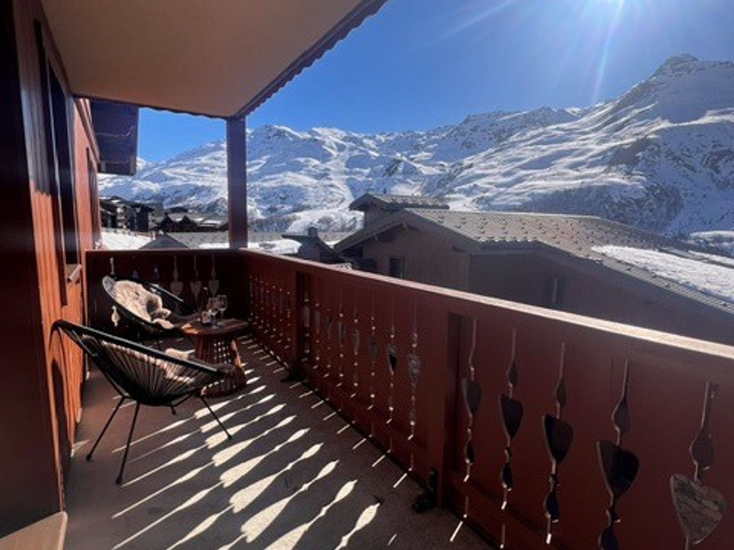 Un balcón con vista a montañas nevadas, una silla y una mesa.