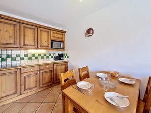 A kitchen with wooden cabinets, a microwave, and a tiled backsplash. - Apartment near slopes with balcony (Les Menuires)