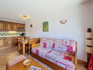 A compact living space with a kitchenette, a sofa, a dining table, and a small coffee table. - Apartment near slopes with balcony (Les Menuires)