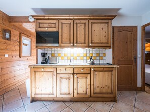 A kitchen with wooden cabinets, a built-in oven, a coffee maker, and a tiled backsplash. - Cozy apartment near slopes - 4 guests (Les Menuires)