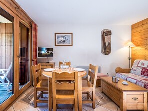 A wooden interior with a dining table, chairs, a sofa, a TV, and a framed picture on the wall. - Cozy apartment near slopes - 4 guests (Les Menuires)