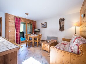Une pièce confortable avec un lit en bois, une table à manger avec des chaises, un téléviseur et un radiateur.