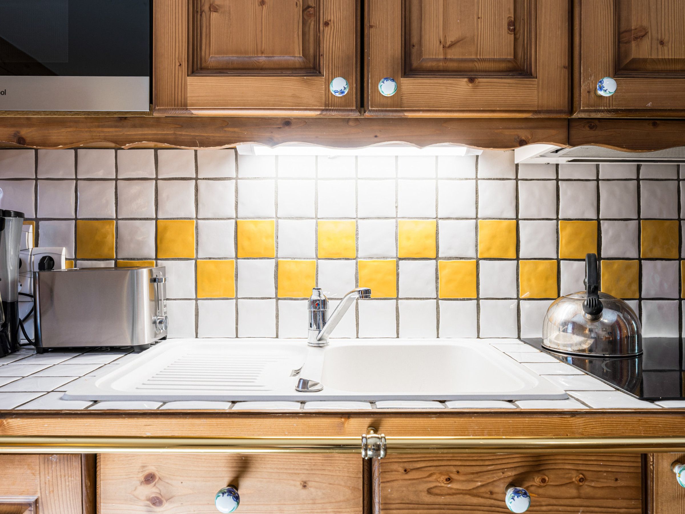 A kitchen with wooden cabinets, a white sink, and a tiled backsplash.