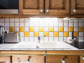 Une cuisine avec des meubles en bois, un évier blanc et un dosseret carrelé.