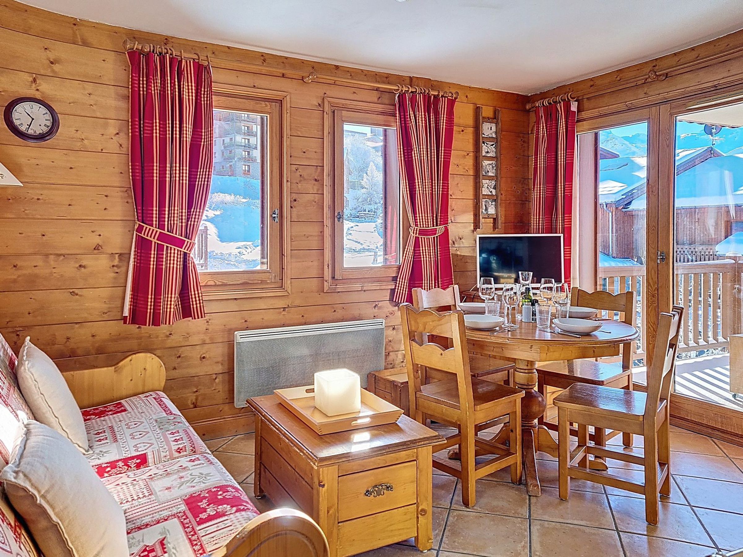 Un ambiente accogliente con pareti in legno, un tavolo da pranzo per due persone, un divano e una televisione.