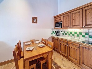 Una cocina pequeña con gabinetes de madera, un microondas y un salpicadero de azulejos.