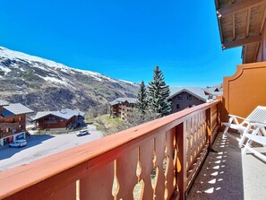 Un balcone con vista su una montagna, edifici in legno e cielo sereno.