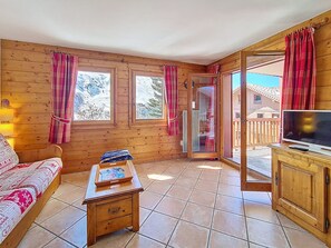 Habitació acollidora amb un llit, una taula petita, un televisor i una porta corredissa de vidre que dona a una zona exterior.