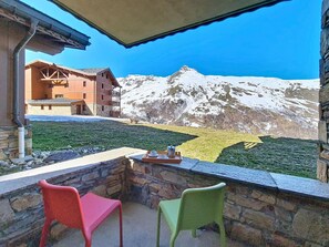 Eine Berglodge mit einer Steinfassade, einem Balkon mit zwei Stühlen und einem Tisch mit einer Kaffeetasse und Untertasse.