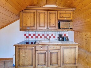 Eine Küche mit Holzschränken, einer gefliesten Spritzschutzwand und einer Arbeitsplatte mit Kaffeemaschine.