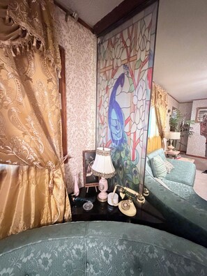 A room with a sofa, a lamp, a telephone, and a decorative wall.