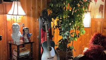 Ein Zimmer mit Holzwandverkleidung, einer Gitarre, einer Lampe, einer Büstenstatue und einem Topfpflanzen.