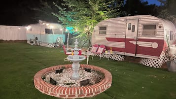 Een verzorgd gazon met een decoratieve fontein en een zitgedeelte, omringd door campers.