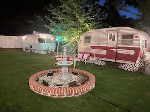 A well-maintained lawn with a decorative fountain and seating area, surrounded by RVs.