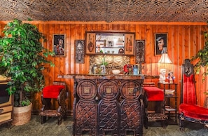 A room with wooden paneling, a bar area with red cushions, and various decorative items.