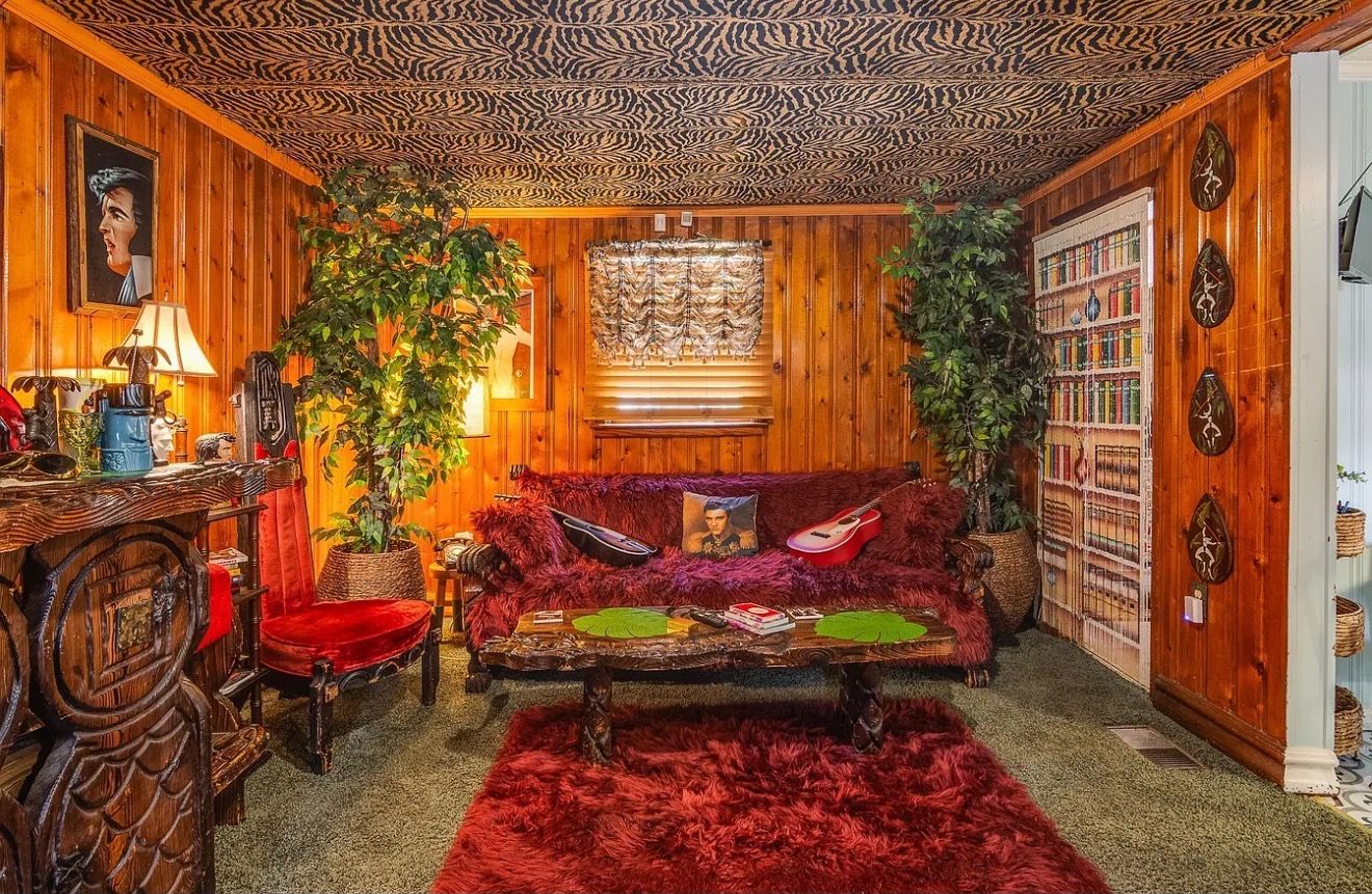 Une pièce chaleureuse avec un plafond en bois, un canapé rouge, une table basse et une bibliothèque.