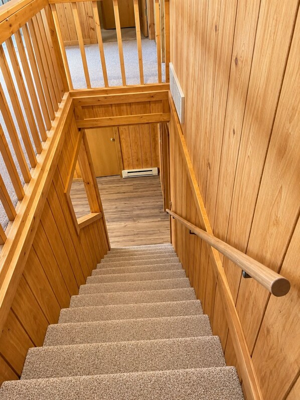 Una escalera de madera con barandilla, escalones alfombrados y paredes de madera.