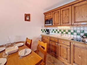Eine Küche mit Holzausstattung, einer Mikrowelle und einer gefliesten Spritzschutzwand.
