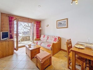 A cozy room with a wooden sofa, a dining table, and a television. - Pleasant apartment near the slopes (Les Menuires)