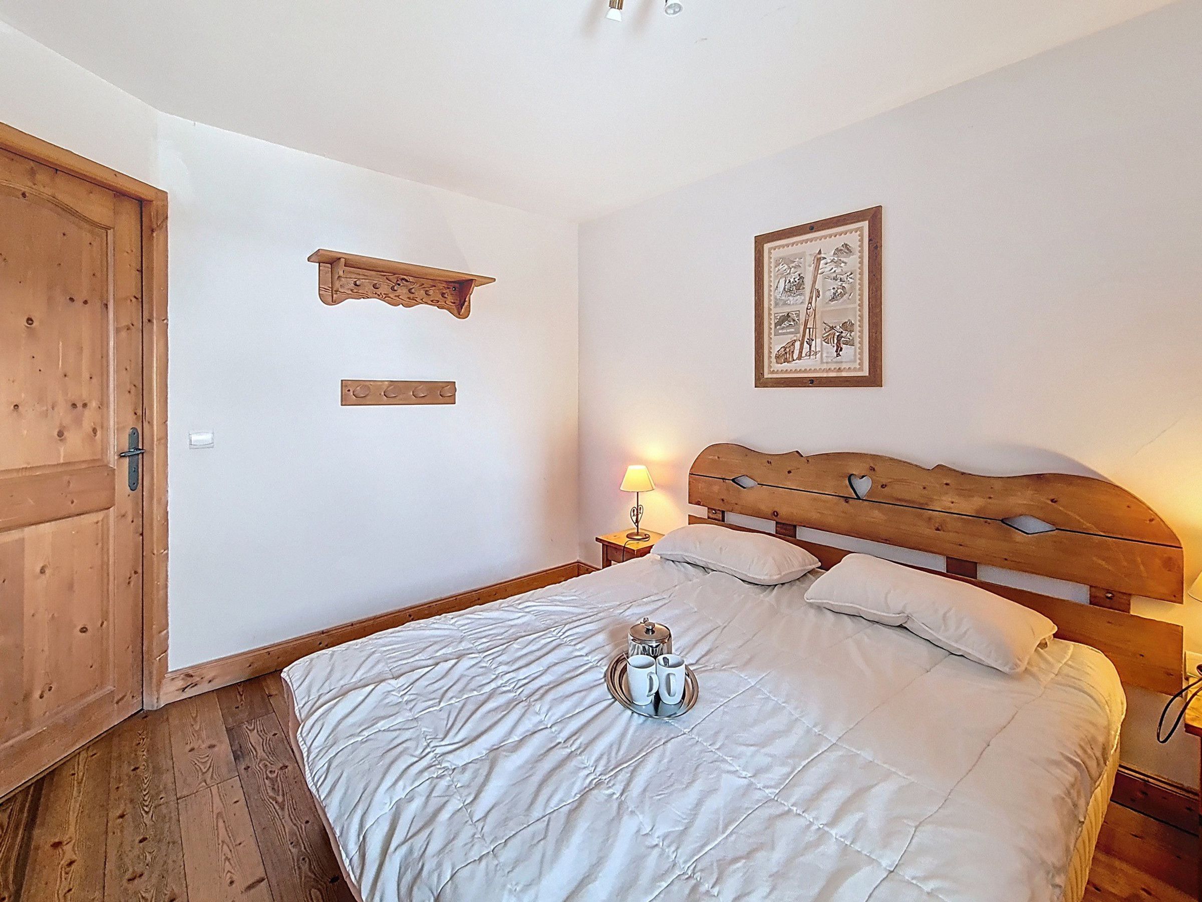 Ein Schlafzimmer mit einem Holzkopfteil, einem Bett mit weißer Bettwäsche, einem Nachttisch mit einer Lampe und einer Holztür.