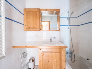 Un baño con tocador de madera, un espejo, un lavabo y una ducha.
