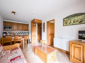 A cozy living room with a wooden sofa, a coffee table, and a television. - Spacious apartment near slopes - 4 guests (Les Menuires)