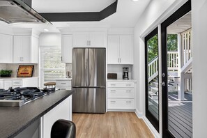 A modern kitchen with white cabinets, a stainless steel refrigerator, and a black countertop.
