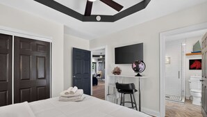 A hotel room with a large bed, a desk with a chair, a flat-screen TV, and a bathroom with a shower and toilet. - Premium waterfront home w/ hot tub & scenic views! (Louisville)