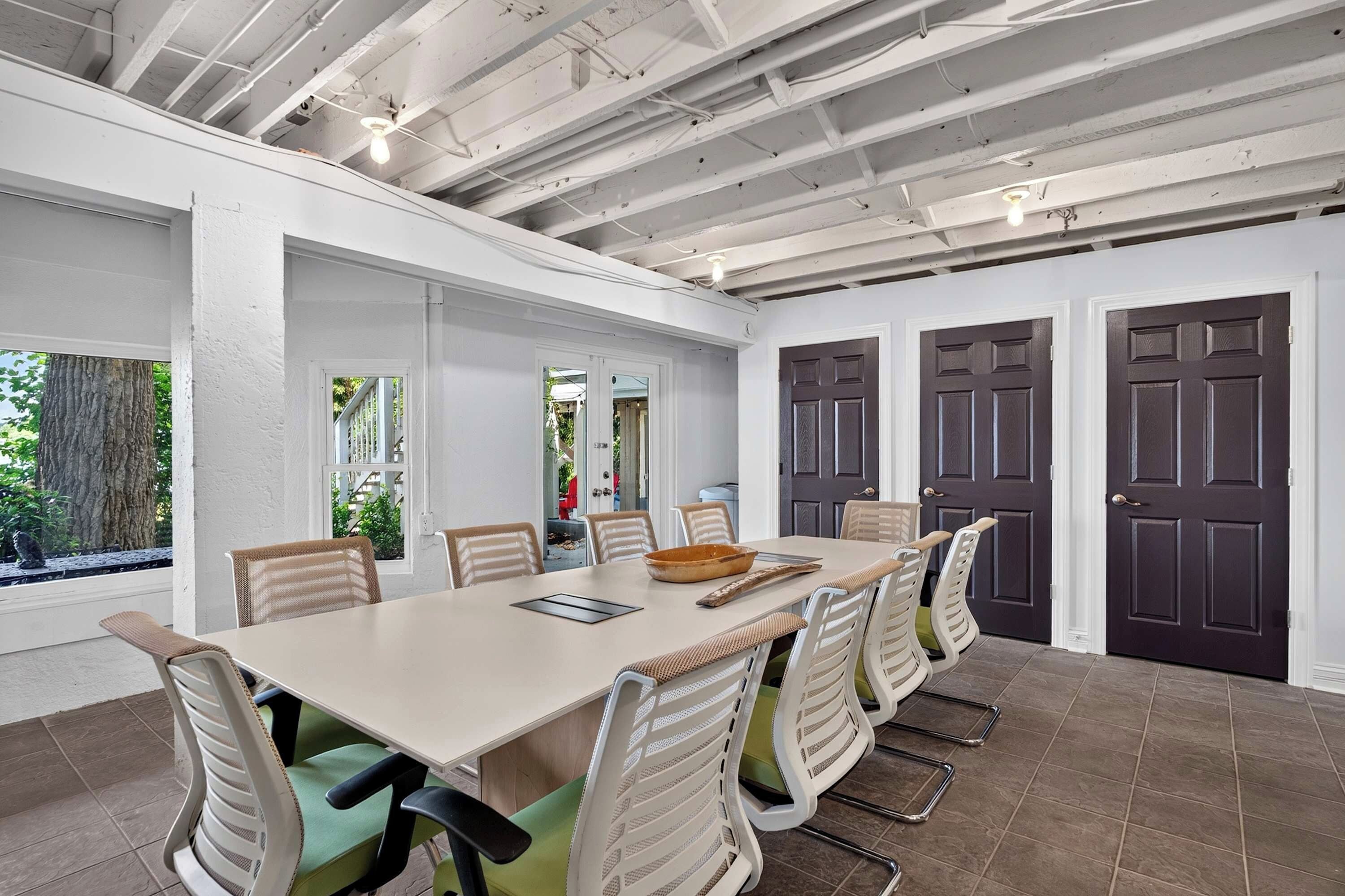 A conference room with a long table, chairs, and a ceiling with exposed beams.