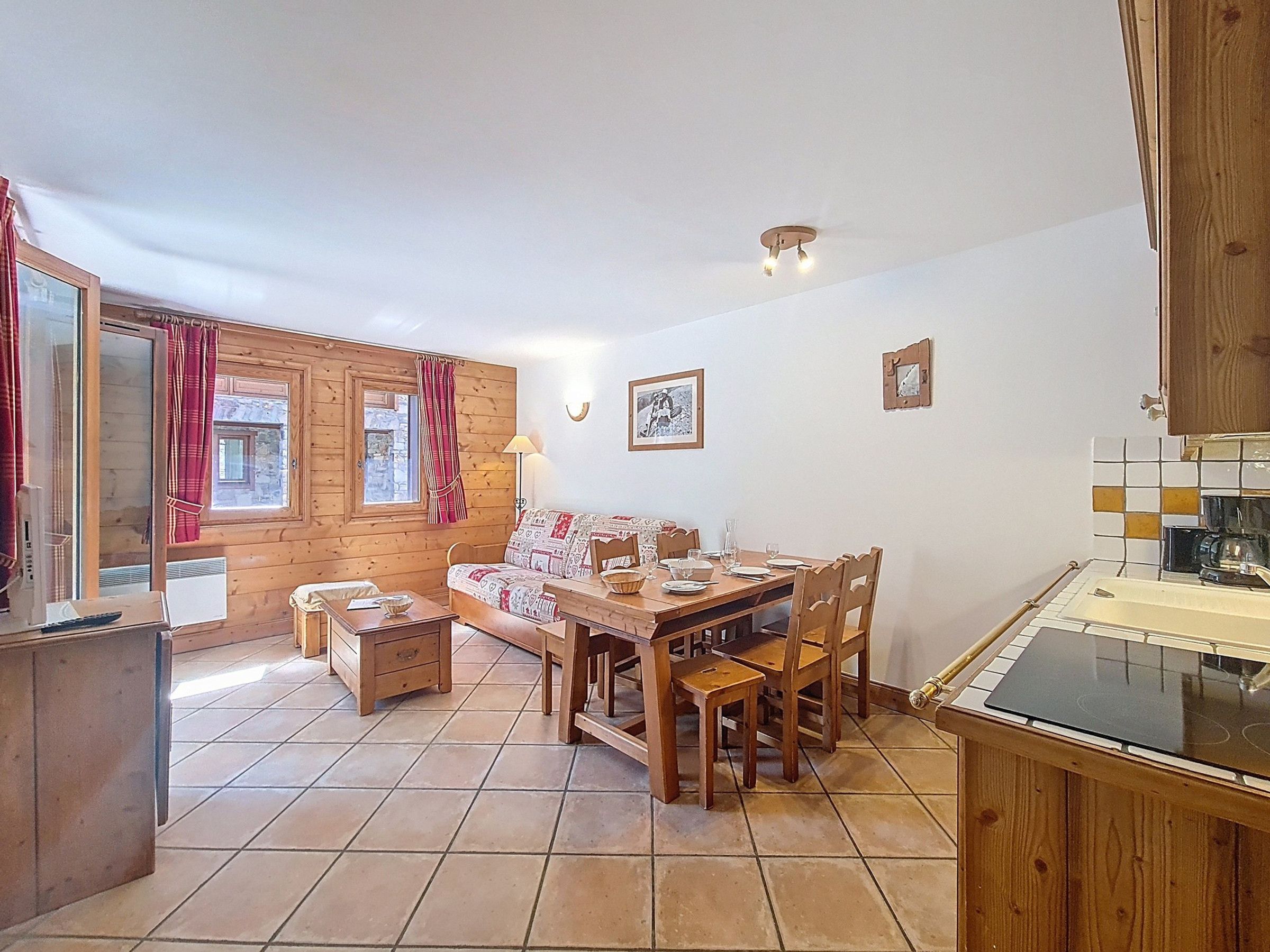 Una habitación acogedora con una mesa de comedor de madera, sillas, un sofá y una zona de cocina con estufa.