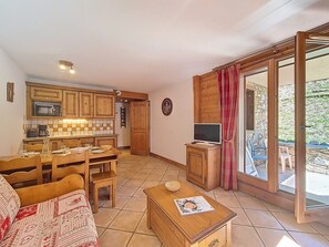 A compact living space with a kitchen, dining area, and a balcony with a stone wall. - Spacious apartment with balcony - 6 guests (Les Menuires)