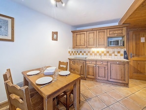 A kitchen with wooden cabinets, a tiled backsplash, and a dining table set for four. - Spacious apartment near slopes - 4 guests (Les Menuires)