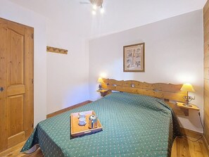 Ein Schlafzimmer mit einem hölzernen Bett, Nachttischlampen, einem gerahmten Bild an der Wand und einem Tablett mit Tassen und einer Kaffeekanne auf dem Bett.
