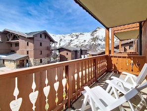 A balcony with white chairs and a view of snow-covered mountains. - Apartment near slopes, balcony (Les Menuires)
