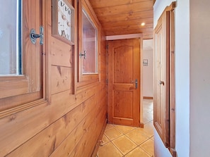 A wooden hallway with a tiled floor, wooden doors, and a window with a view of the outside. - Apartment near slopes, balcony (Les Menuires)