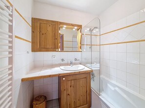 Ein Badezimmer mit einem Holzbadezimmermöbel, einem Waschbecken, einem Spiegel, einer Dusche und einer Badewanne.