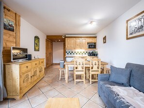 Ett kompakt bostadsutrymme med ett litet kök, en matplats och en soffa.